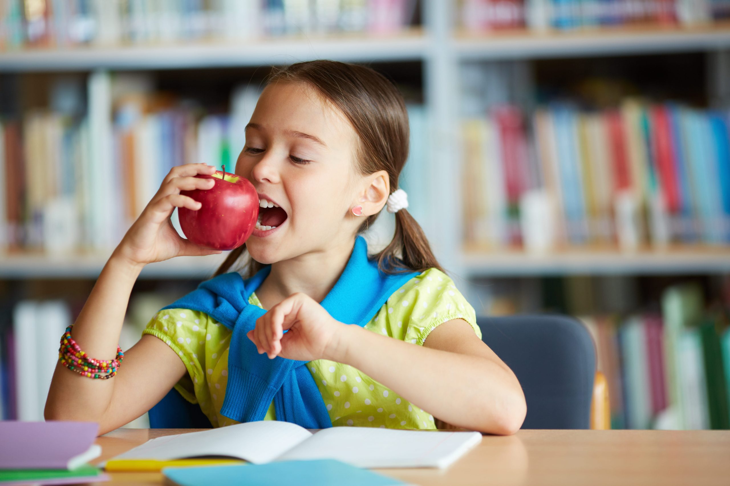 Niña en una clase comiendo una manzana